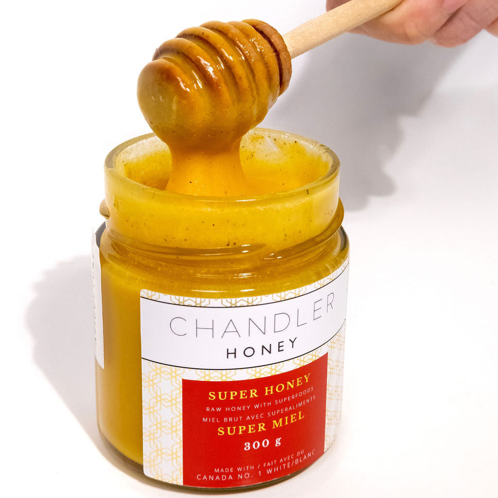 Jar of Super Honey with a wooden dipper on a white background